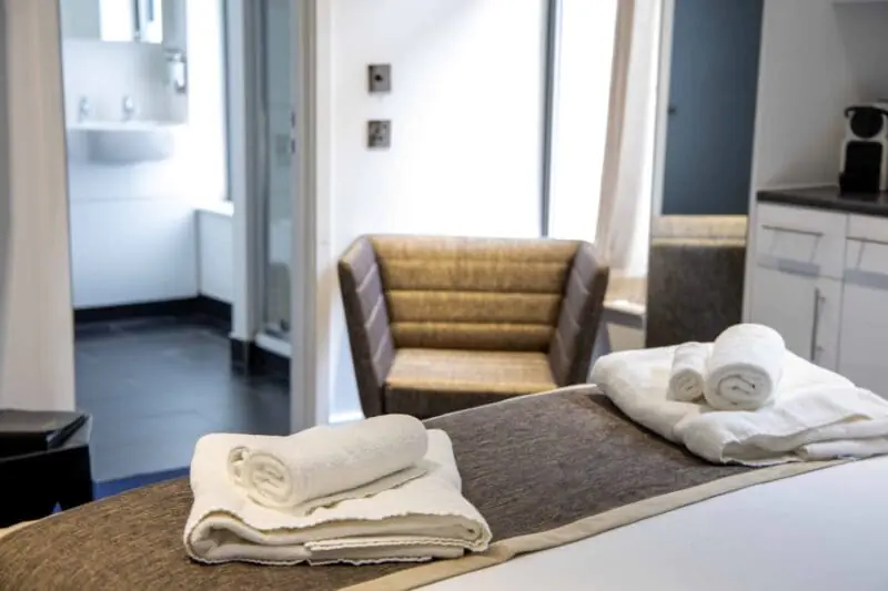 Boutique overnight accommodation at Office Space in Town Monument, showcasing the Hesperus room with a plush double bed, porthole style windows, and a sophisticated atmosphere for a restful stay.