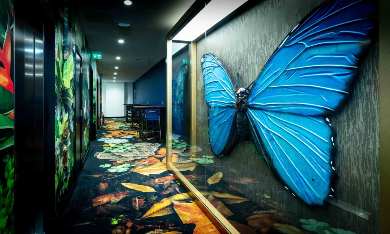 Modern breakout area at Office Space in Town Blackfriars featuring a giant butterfly wall art, vibrant furniture, and biophilic design elements designed to boost employee wellbeing and productivity.