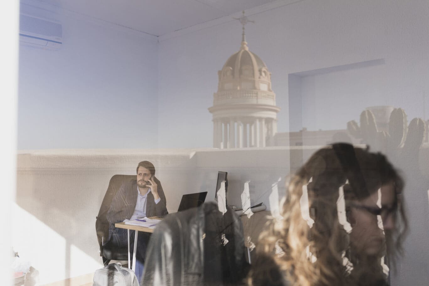 Serious woman and man talking on smartphone and using laptop at workplaces